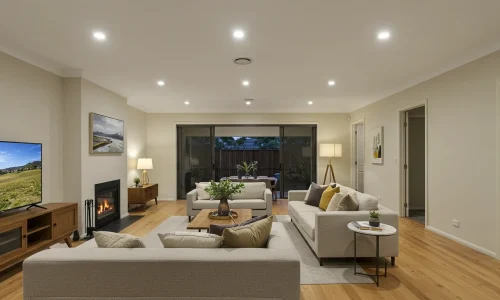 Spacious modern living room with comfortable sofas, a TV, and large windows leading to a backyard.